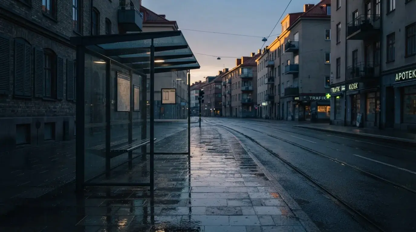 Pusta wiata przystanku tramwajowego na miejskiej ulicy o świcie, pusta ławka i mokry chodnik.