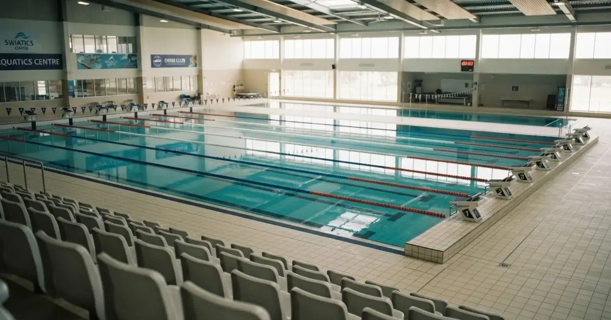 Pusty basen olimpijski z równymi torami i spokojną taflą wody, widok z trybun w jasnym świetle.